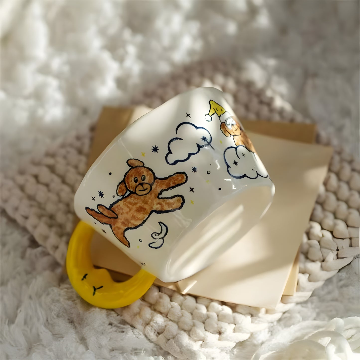 a moon shaped handle cearmic mug with blue moon, cloud, a dog and stars on top of a crocheted rug 