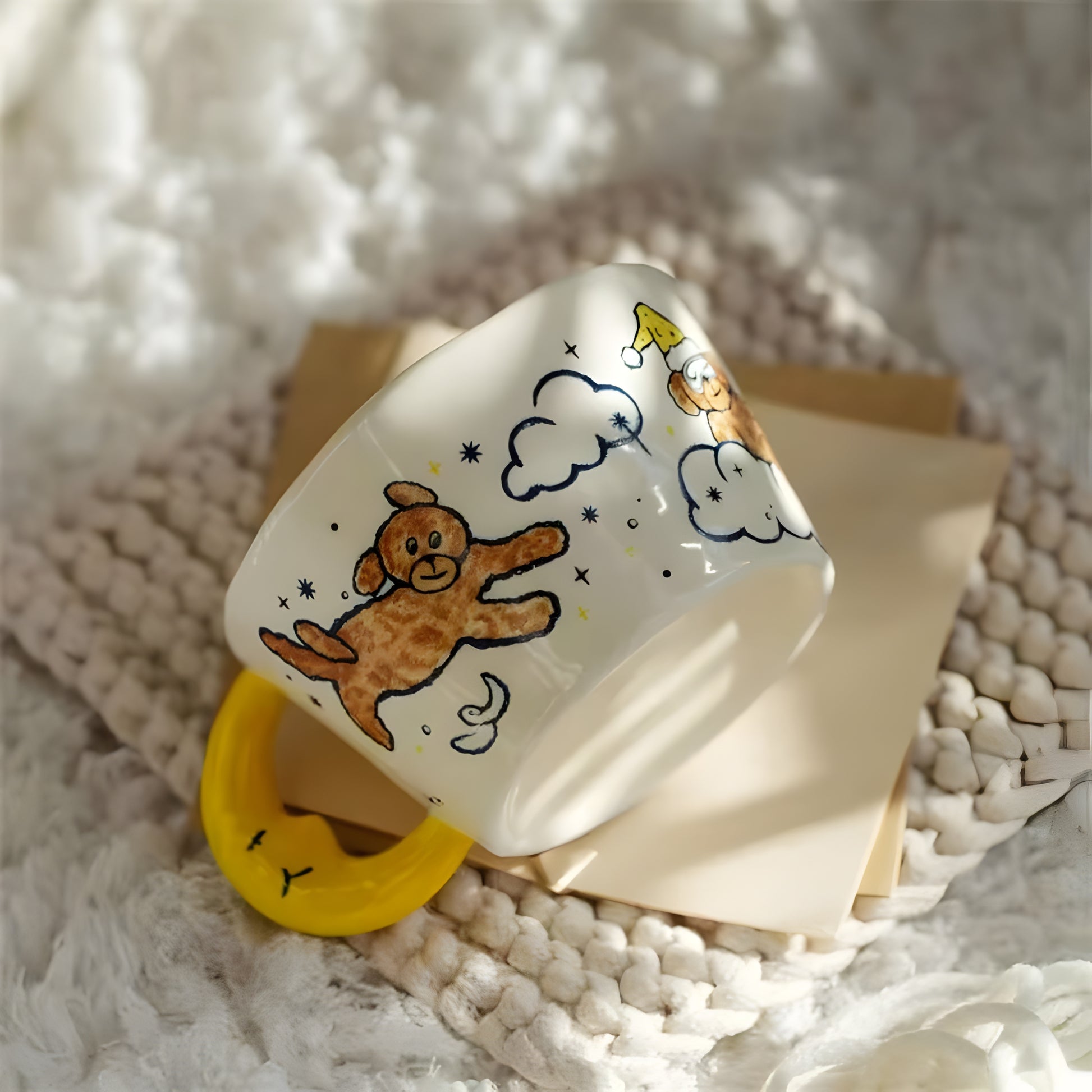 a moon shaped handle cearmic mug with blue moon, cloud, a dog and stars on top of a crocheted rug 