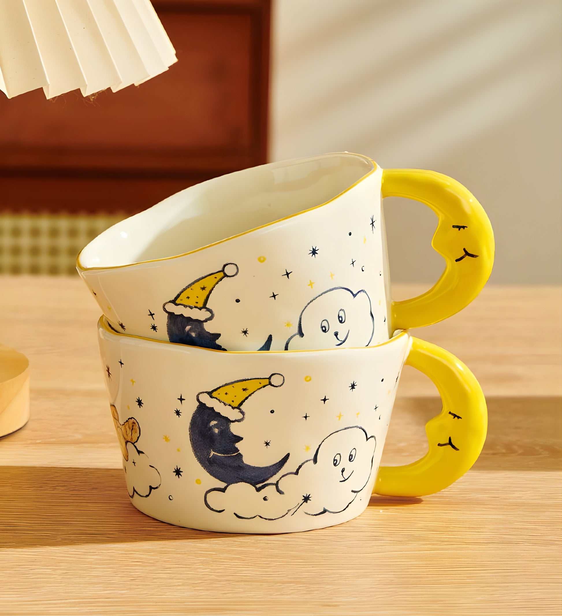 2 moon shaped handle cearmic mug with blue moon, cloud, a dog and stars stacking on a wood table, warm light reflecting in the back with a cozy vibe